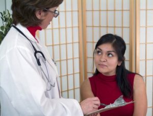 Doctor taking notes on a clipboard while the patient listens