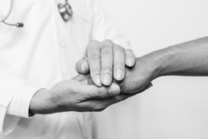 A doctor holding patient's hand to calm him.